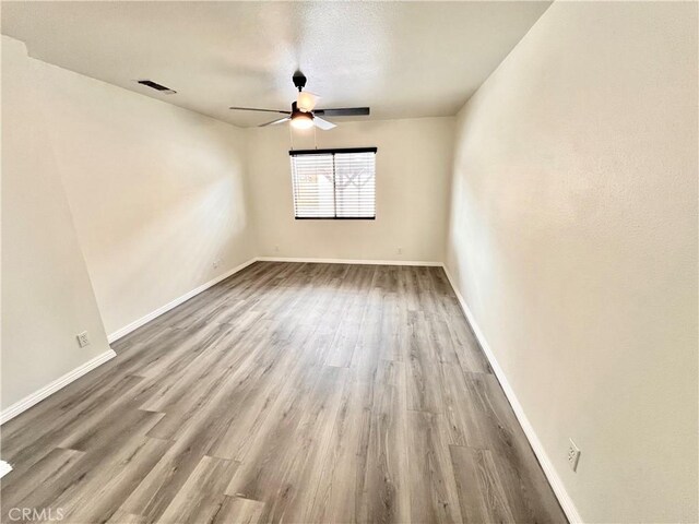 empty room featuring visible vents, baseboards, ceiling fan, and wood finished floors