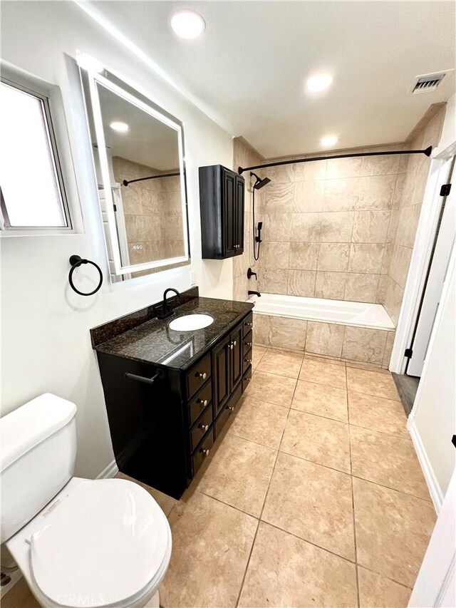 bathroom with visible vents, vanity, toilet, tile patterned floors, and tiled shower / bath combo