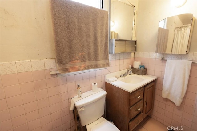 full bath with tile walls, a wainscoted wall, vanity, and toilet