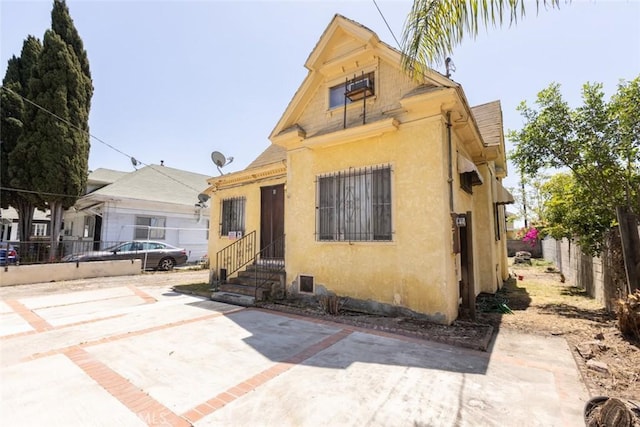 bungalow-style home featuring fence, a patio, stucco siding, and entry steps