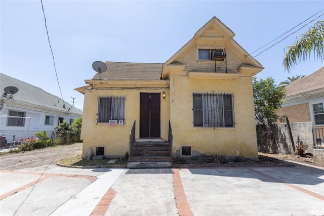 bungalow with fence, entry steps, and stucco siding