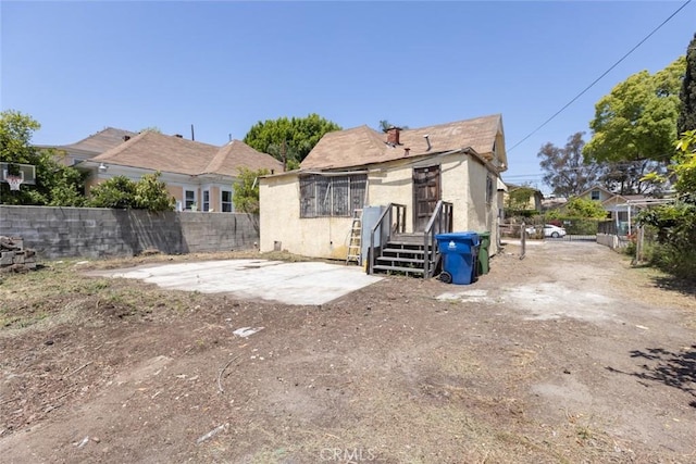 rear view of house with stucco siding, a patio area, and fence
