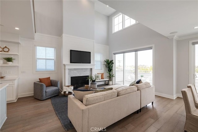 1524 Wollacott St, Redondo Beach, CA 90278 - living area with a brick fireplace, light wood-style flooring, a towering ceiling, baseboards, and ornamental molding
