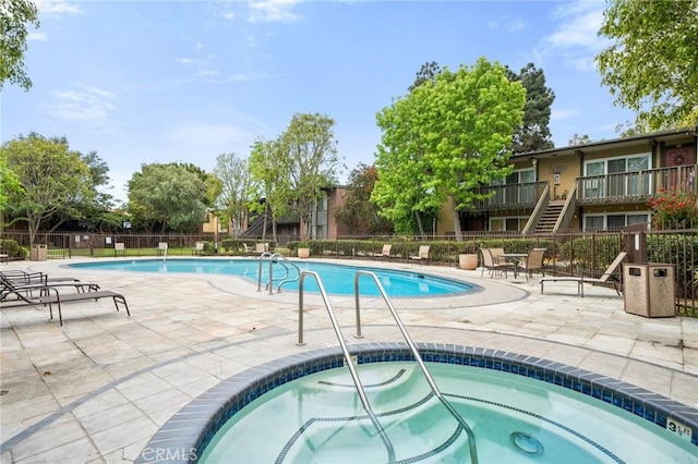 community pool featuring a patio, fence, and a community hot tub