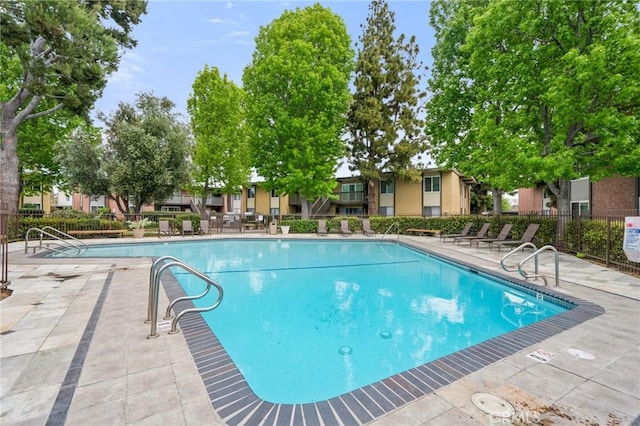 community pool with fence, a patio area, and a residential view