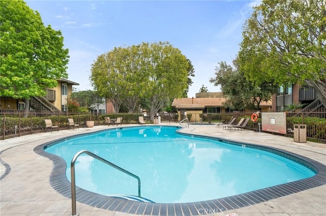 community pool with fence and a patio