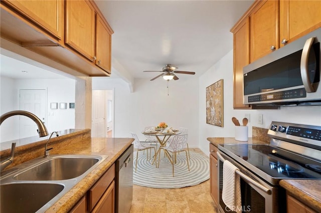 kitchen with a ceiling fan, a sink, appliances with stainless steel finishes, and brown cabinets