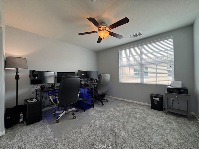 carpeted home office with baseboards, ceiling fan, and visible vents