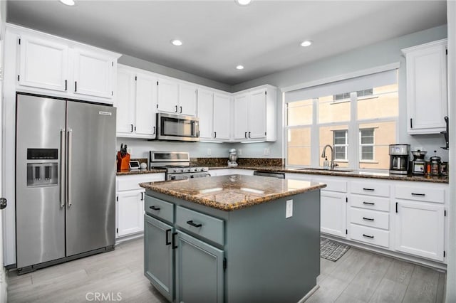 kitchen with dark stone counters, white cabinetry, appliances with stainless steel finishes, and a sink