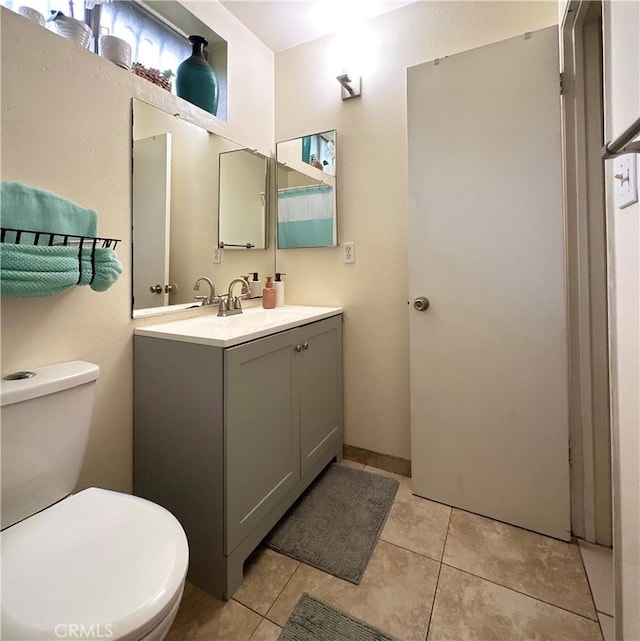 bathroom with toilet, tile patterned floors, and vanity