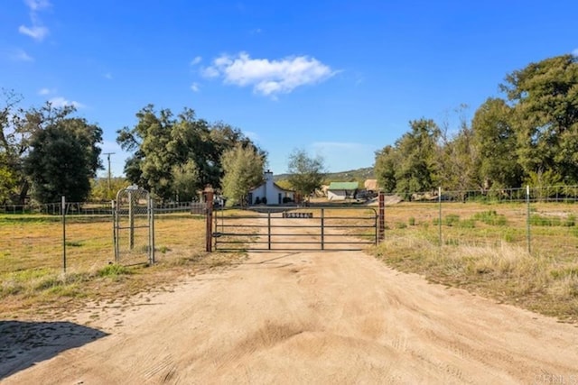 view of road featuring a rural view, driveway, a gated entry, and a gate