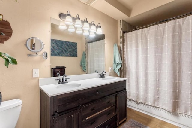 bathroom featuring double vanity, toilet, a sink, and shower / tub combo with curtain