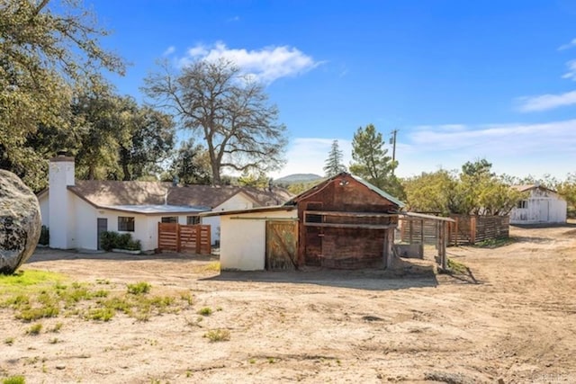 exterior space featuring fence, an outbuilding, and a chimney