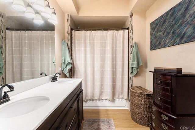 full bathroom featuring a sink, a shower with curtain, double vanity, and wood finished floors