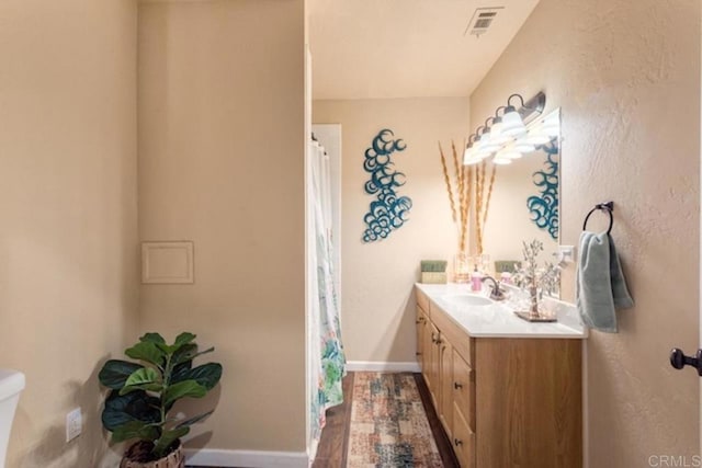 bathroom with vanity, baseboards, toilet, and visible vents