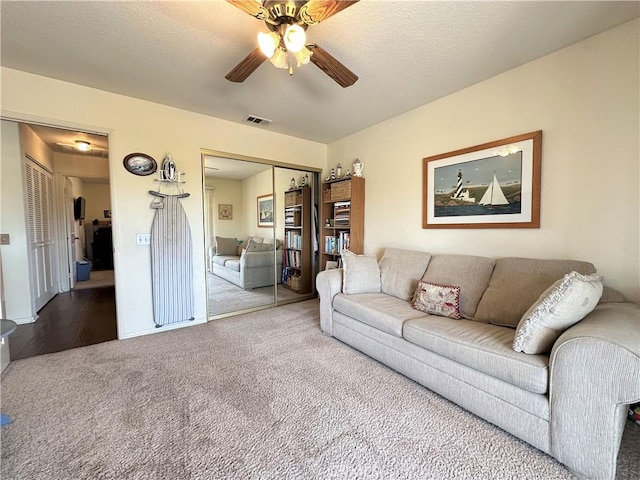 living area with a ceiling fan, visible vents, and carpet