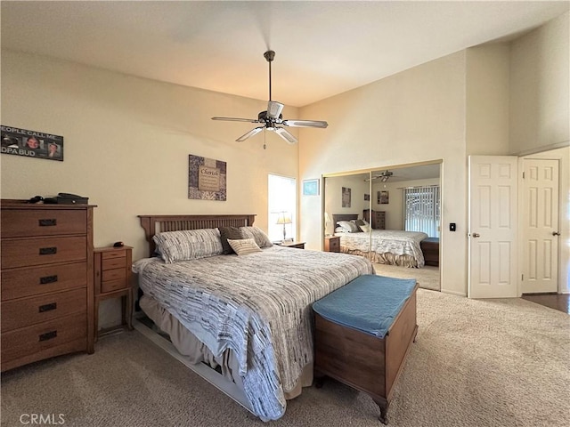 carpeted bedroom with a closet, a ceiling fan, and a towering ceiling