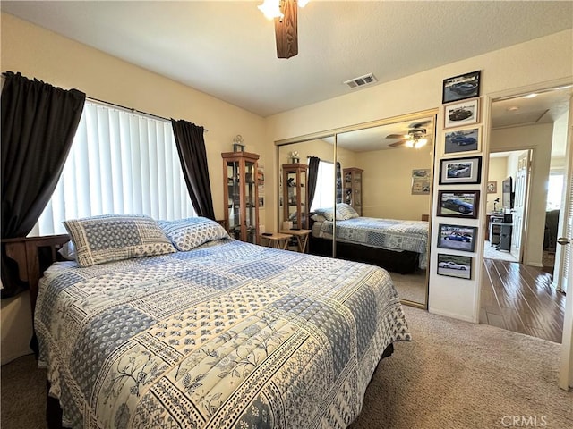 carpeted bedroom featuring visible vents, a ceiling fan, and a closet