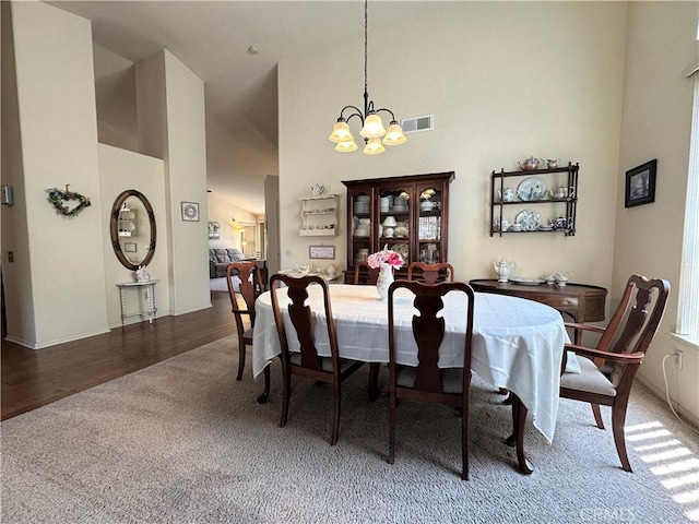 dining room featuring an inviting chandelier, high vaulted ceiling, carpet flooring, and visible vents