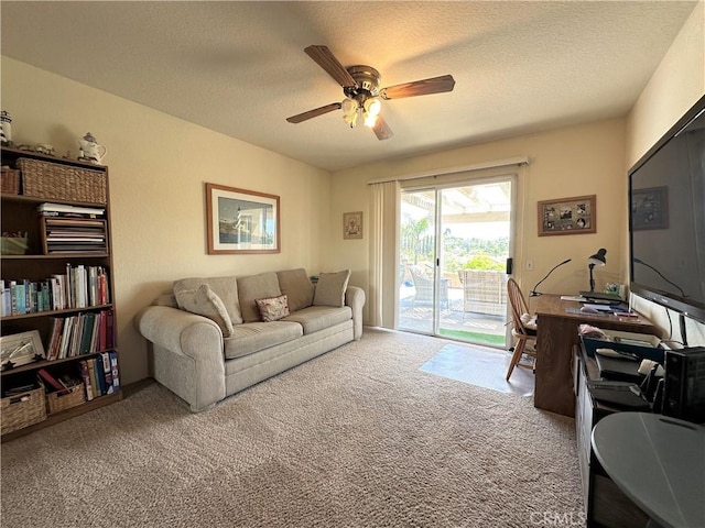 living area featuring carpet, a ceiling fan, and a textured ceiling