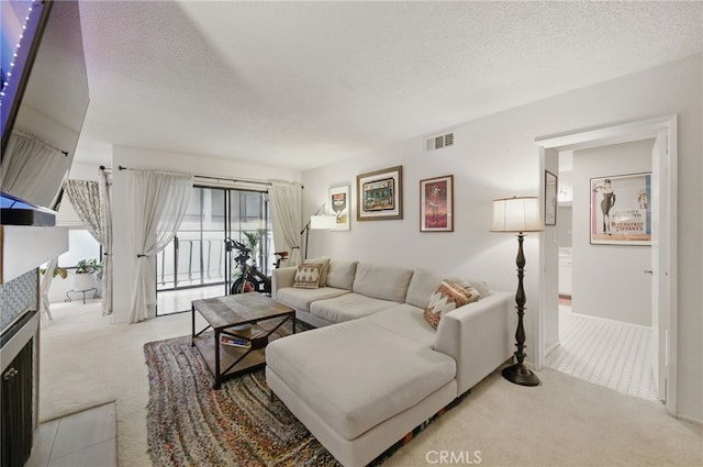 carpeted living room with visible vents, a textured ceiling, and a tiled fireplace