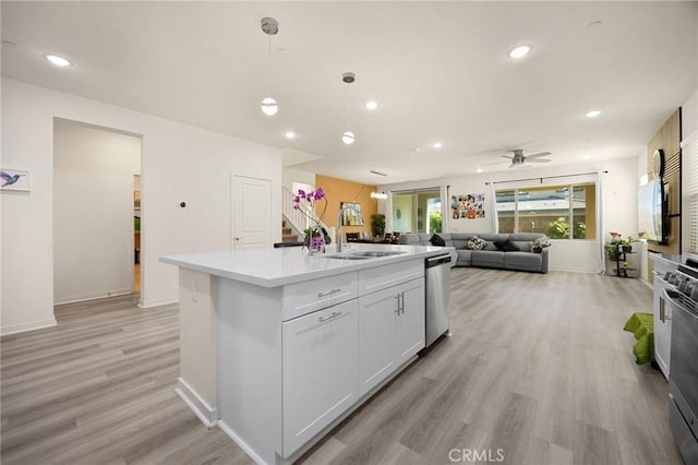 kitchen featuring ceiling fan, a sink, light wood finished floors, light countertops, and stainless steel dishwasher