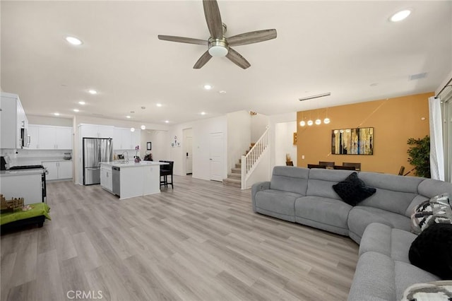 living room with recessed lighting, a ceiling fan, light wood finished floors, and stairway