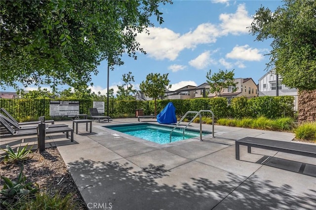 view of swimming pool with a patio, a swimming pool, fence, and a residential view