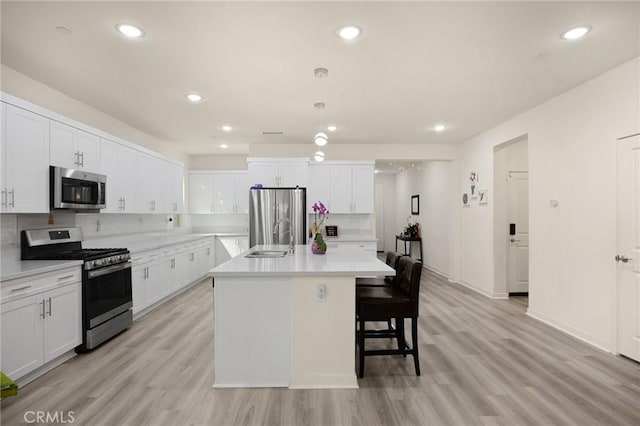 kitchen featuring decorative backsplash, appliances with stainless steel finishes, light countertops, a sink, and white cabinets