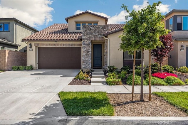 mediterranean / spanish house with a tile roof, concrete driveway, an attached garage, stone siding, and stucco siding
