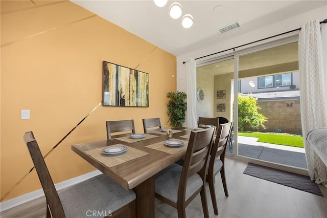 dining area with baseboards, visible vents, and wood finished floors