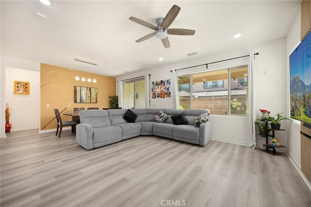 living area featuring a ceiling fan, visible vents, baseboards, light wood finished floors, and recessed lighting