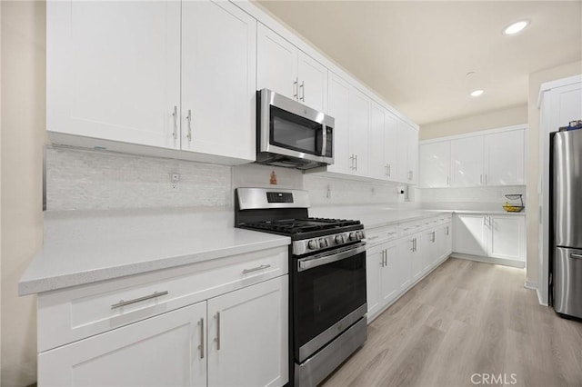 kitchen featuring light countertops, tasteful backsplash, stainless steel appliances, and white cabinetry