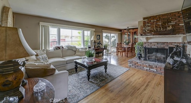 living area featuring a brick fireplace, a ceiling fan, and wood finished floors