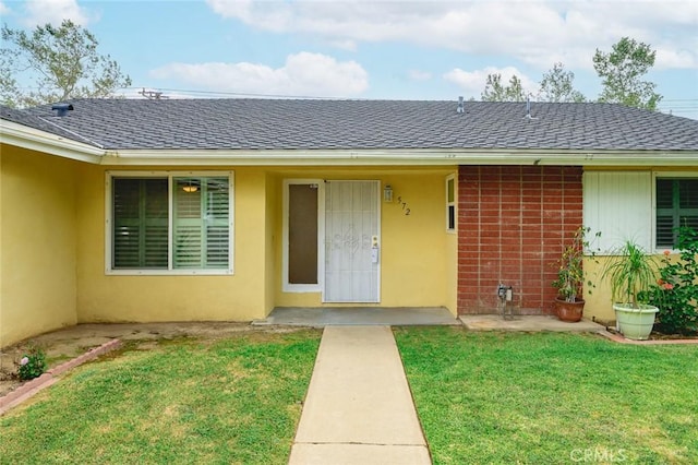572 E Ghent St, San Dimas, CA 91773 - view of exterior entry featuring a yard and a shingled roof