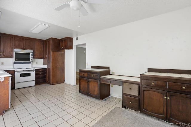 kitchen featuring ceiling fan, light countertops, stainless steel microwave, electric stove, and light tile patterned floors