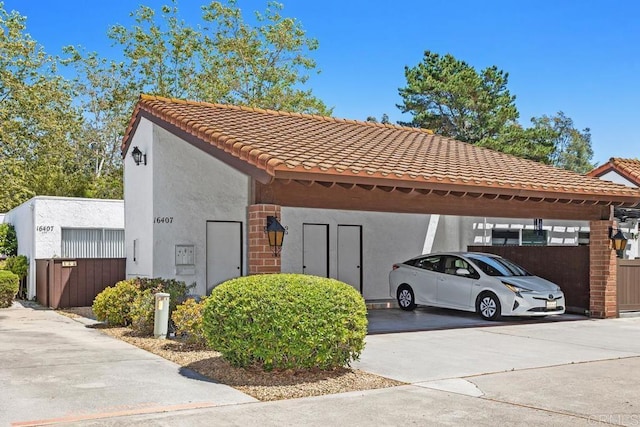 view of home's exterior with covered parking, stucco siding, a tile roof, and fence