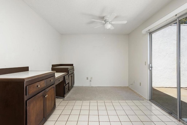 kitchen with dark brown cabinetry, a ceiling fan, a textured ceiling, light countertops, and light carpet