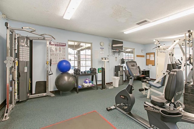 gym featuring baseboards, a textured ceiling, visible vents, and a wealth of natural light
