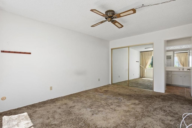 unfurnished bedroom with a sink, carpet floors, a textured ceiling, a ceiling fan, and a closet