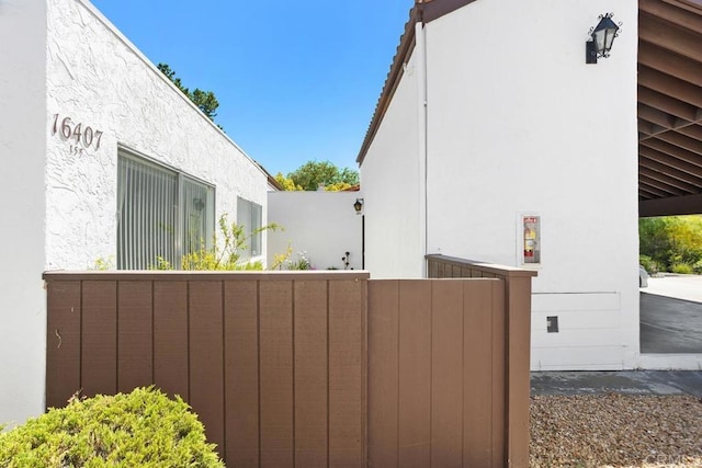view of side of home featuring fence and stucco siding