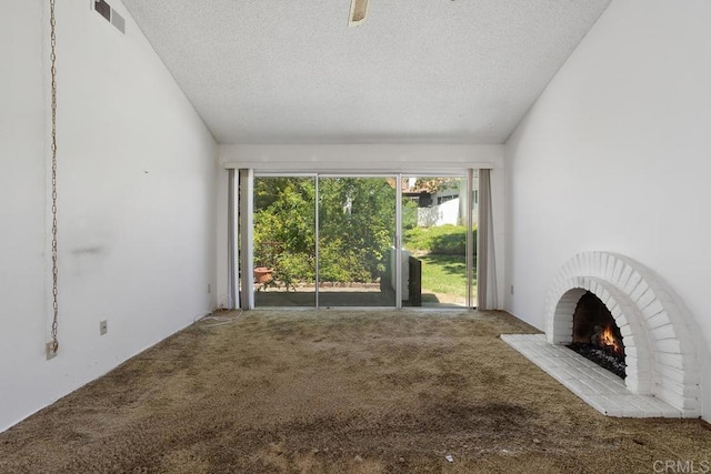 unfurnished living room with a textured ceiling, visible vents, a fireplace, carpet floors, and lofted ceiling