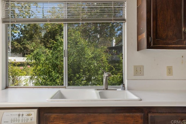 room details with a sink, light countertops, white dishwasher, and dark brown cabinetry