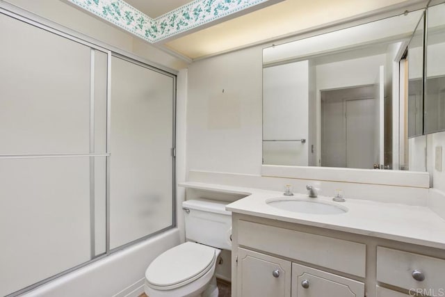 bathroom featuring vanity, enclosed tub / shower combo, and toilet