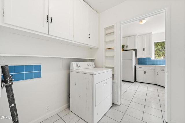 clothes washing area with cabinet space, light tile patterned flooring, baseboards, and washer / dryer