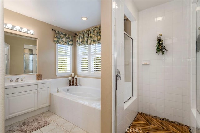 bathroom featuring tile patterned flooring, a bath, a tile shower, and vanity