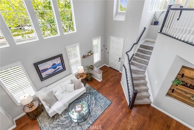 interior space with baseboards, a high ceiling, stairs, and wood finished floors