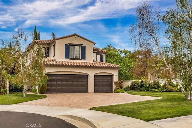 mediterranean / spanish house featuring a tiled roof, a garage, decorative driveway, a front lawn, and stucco siding