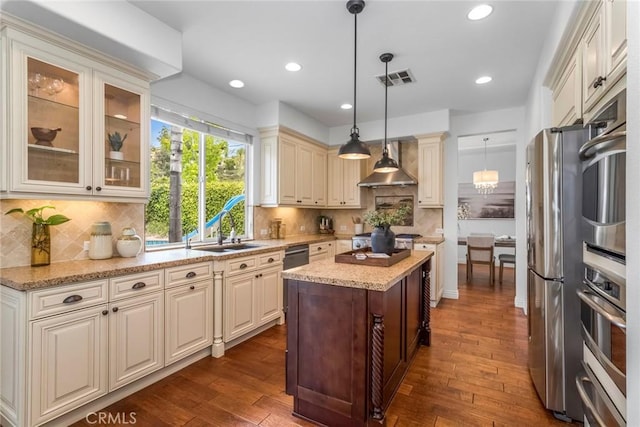 kitchen featuring visible vents, a kitchen island, dark wood-style floors, wall chimney range hood, and stainless steel appliances