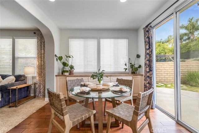 dining space with recessed lighting, arched walkways, and light wood-type flooring
